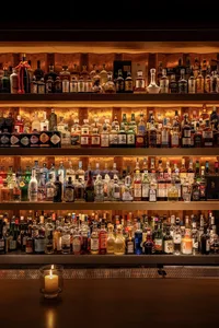 A bar area with wooden shelves displaying a collection of liquor bottles in a visually appealing arrangement, creating a warm and inviting atmosphere