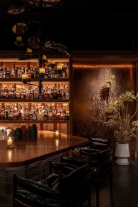 Warm and inviting bar area with a wooden table, candles, and bottles, set in a restaurant