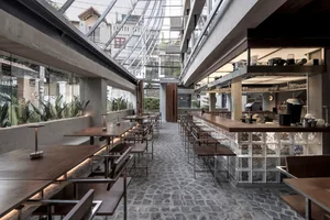 Inviting restaurant interior with stone flooring, multiple tables, chairs, and potted plants