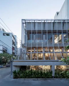 A modern building with multiple levels, featuring a mix of concrete, glass, and wood materials, with chairs and a contemporary design