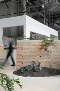 A modern restaurant interior with a brick wall, potted plants, and a white color scheme, creating a clean and bright atmosphere