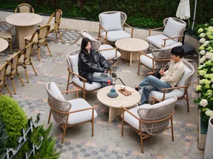 A well-lit outdoor patio with multiple chairs, dining tables, and potted plants, featuring a relaxed and social atmosphere