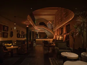 Elegant living space with a spiral staircase made of wood, metal railing, two chairs, and potted plants, well lit and inviting