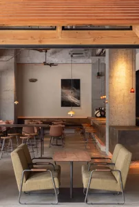 Modern restaurant interior with dining tables, chairs, and potted plants, creating a comfortable atmosphere