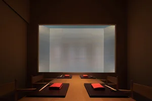 Cozy dining space with a long wooden table, red napkins, and dim lighting