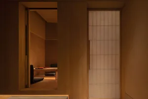 A modern living space with wooden walls and floors, featuring two couches and a chair, giving off a cozy and comfortable atmosphere