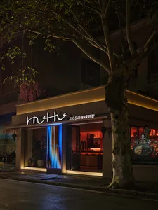 A modern Asian restaurant with a bar area, large window, and warm ambiance, featuring wood elements and potted plants