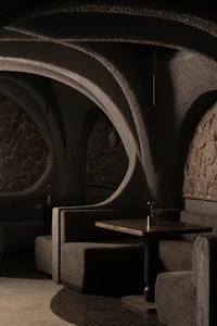 Inviting restaurant interior with stone walls, cement elements, and comfortable seating areas
