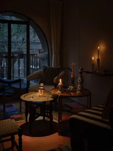 A cozy dining space with a wooden table and chairs, a couch in the background, and a potted plant, with candles adding to the intimate atmosphere