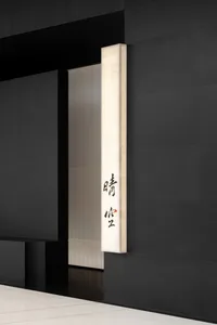 Elegant interior space with a black wall featuring a white marble accent, two doors with distinct designs, and a focus on clean lines and minimalist elements