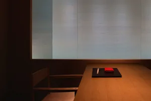 Empty dining area with a wooden table and two chairs, set for a meal with a red napkin, creating a calm and inviting atmosphere