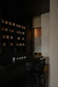 A simple Asian-style dining area with a black table, two chairs, and a cozy atmosphere