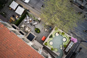 A large patio area with potted plants, chairs, umbrellas, and dining tables, creating a relaxing and inviting atmosphere