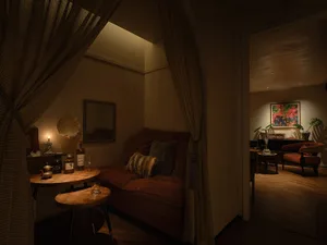 Cozy living space with a couch, chairs, dining table, and potted plant, featuring a warm and inviting atmosphere