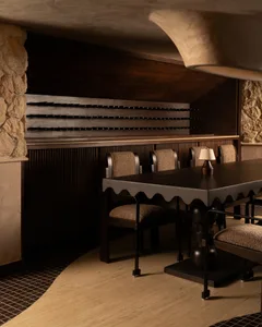 A darkly lit dining area with a large wooden table surrounded by multiple chairs, creating a cozy and intimate atmosphere for meals with friends and family