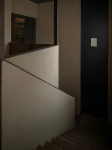 A photo of a staircase in a modern building with wooden stairs and a black wall, creating a sense of depth and dimension