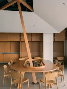 Open modern dining space with a large wooden dining table and multiple chairs, well-lit by natural light