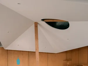 A wooden ceiling with a large central opening creates a sense of openness in this interior design concept