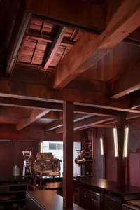 Industrial workspace with a large wooden beam, two vintage and modern coffee makers, and a rustic atmosphere
