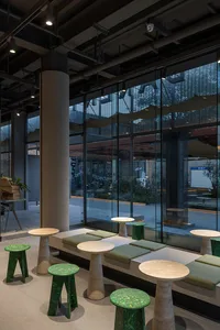 明亮餐廳內部，自然光線、多張餐桌與綠色坐墊