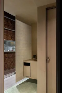 Small bathroom with brown tile walls, a sink, toilet, and shower area, featuring a potted plant on the countertop