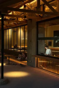 A bustling cafe with people eating, working, and socializing in a modern space with comfortable seating and technology
