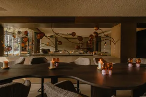 Elegant dining space with a wooden table surrounded by chairs and wine glasses, with a sophisticated ambiance