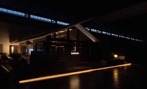 Sleek modern building with a black facade, white trim, and lit windows at night