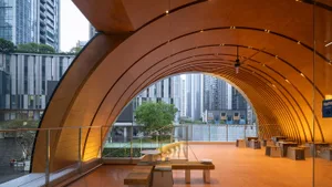 Comfortable living and dining area with wooden floors, a bench, and a table, featuring a large glass wall with a city view