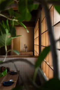 Cozy living space with wooden walls and floors, featuring a potted plant, vases, and a bowl, with a warm and inviting atmosphere