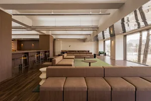 A modern living space with a large couch, chairs, dining tables, and a potted plant, creating a comfortable and inviting atmosphere