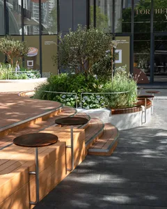 A relaxed outdoor seating area with wooden benches and tables, surrounded by greenery
