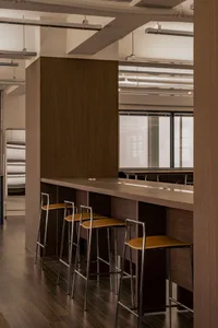 Warm and inviting kitchen with wooden floors, walls, and countertops, featuring a bar with stools and three chairs