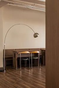 A restaurant interior with wooden floors and walls, featuring various chairs and tables with lamps, creating a warm and inviting atmosphere