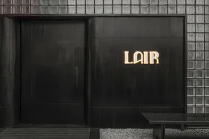 Modern building exterior with a black doorway and a sign reading LAIR above it