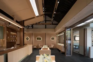 A large open space with wooden walls and ceiling, featuring chairs and dining tables, creating an inviting atmosphere for visitors to view artwork or exhibits