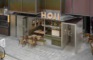 Outdoor restaurant with a modern design featuring a bar area, chairs, and dining tables, with wine bottles adding to the ambiance