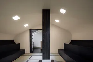 Dimly lit living space with two couches and a wooden pillar, creating a cozy atmosphere