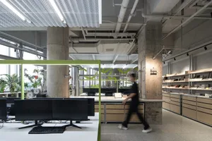 A professional office space with modern furniture, multiple TV screens, and a person walking through the room, conveying a sense of functionality and organization