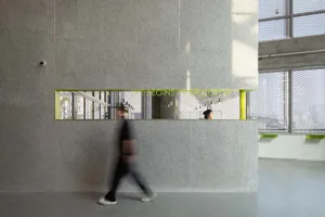 A man walks down a professional office hallway with two other people present, surrounded by a focused work environment