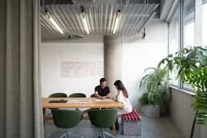 A professional office space with a table and chairs, a whiteboard wall, and two potted plants, creating a focused atmosphere