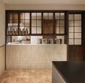 A well-equipped kitchen with tiled floors and walls, featuring pots and pans on the countertops in a clean and organized atmosphere