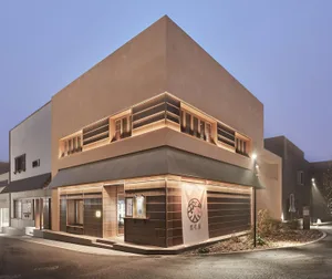 Modern Asian building with a brown exterior, featuring a large window on its side and two smaller windows in the front