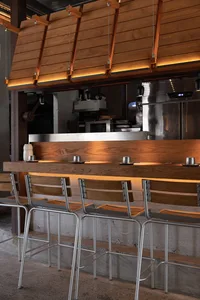 A welcoming bar area with a long wooden counter and several stools, surrounded by chairs in a comfortable and social setting