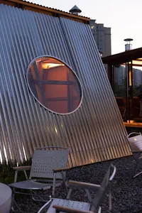 A modern dome-shaped building with a metal exterior, featuring a seating area with chairs and a couch, conveying a sense of innovation and creativity in design