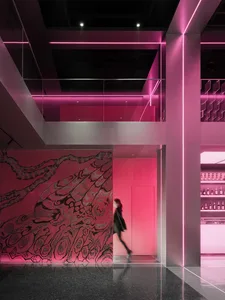 A modern interior space with pink walls and floors, featuring bottles and a creative atmosphere