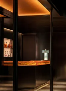 A dark bar area with a countertop featuring various bottles of liquor, creating a cozy and intimate atmosphere for patrons to enjoy their drinks