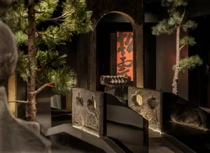 Elegant living and dining space with a black and white color scheme, stone pillars, and a potted plant, featuring a sophisticated atmosphere