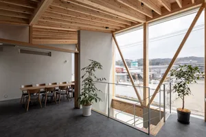 Warm and inviting living area with wood flooring and walls, featuring a dining table, chairs, and a potted plant