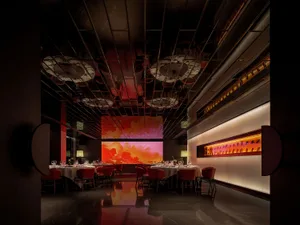 A modern restaurant interior with multiple tables, chairs, wine glasses, and artwork, set in a warm and inviting atmosphere with clean lines and minimalist decoration